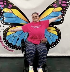 Weekly Warrior Autumn in a pink shirt with a butterfly design behind her